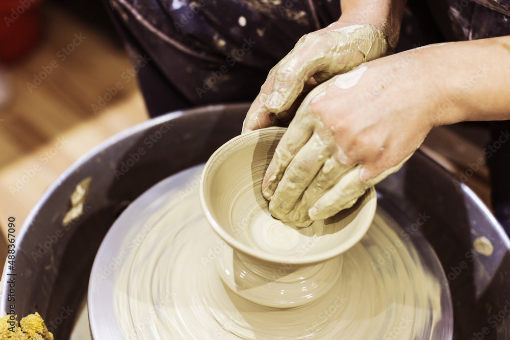 Pottery workshop. Female ceramic artist molding clay on pottery wheel. Creative handmade craft.