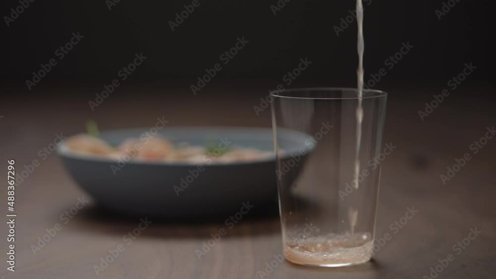 Slow motion pour grapefruit drink in tumbler glass with blue bowl on background Slow motion pour grapefruit drink in tumbler glass with blue bowl on background