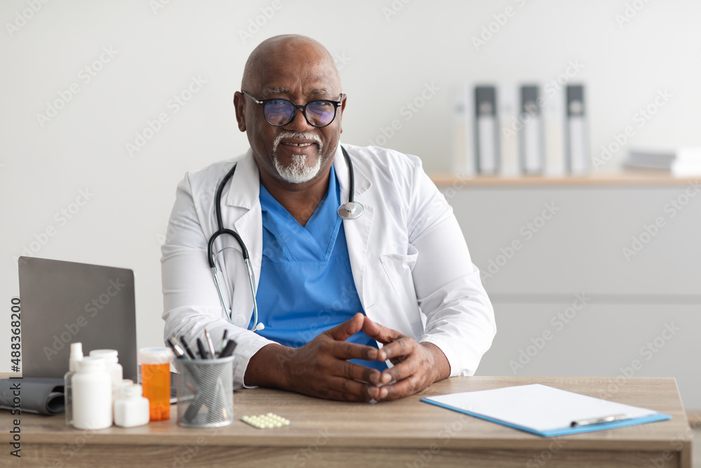Portrait of smiling doctor looking at camera sitting at desk Portrait of smiling doctor looking at camera sitting at desk