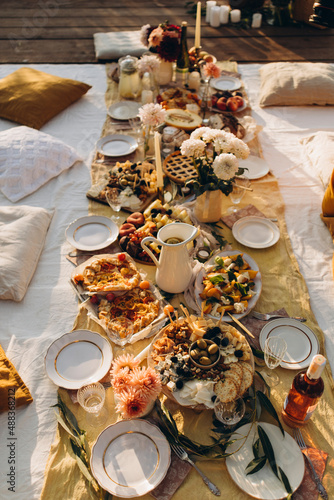 picnic outdoors top view. evening picnic party with golden sunlight. appetizers for outdoor parties. summer picnic snacks with fruits, cheeses and pies and rose wine.