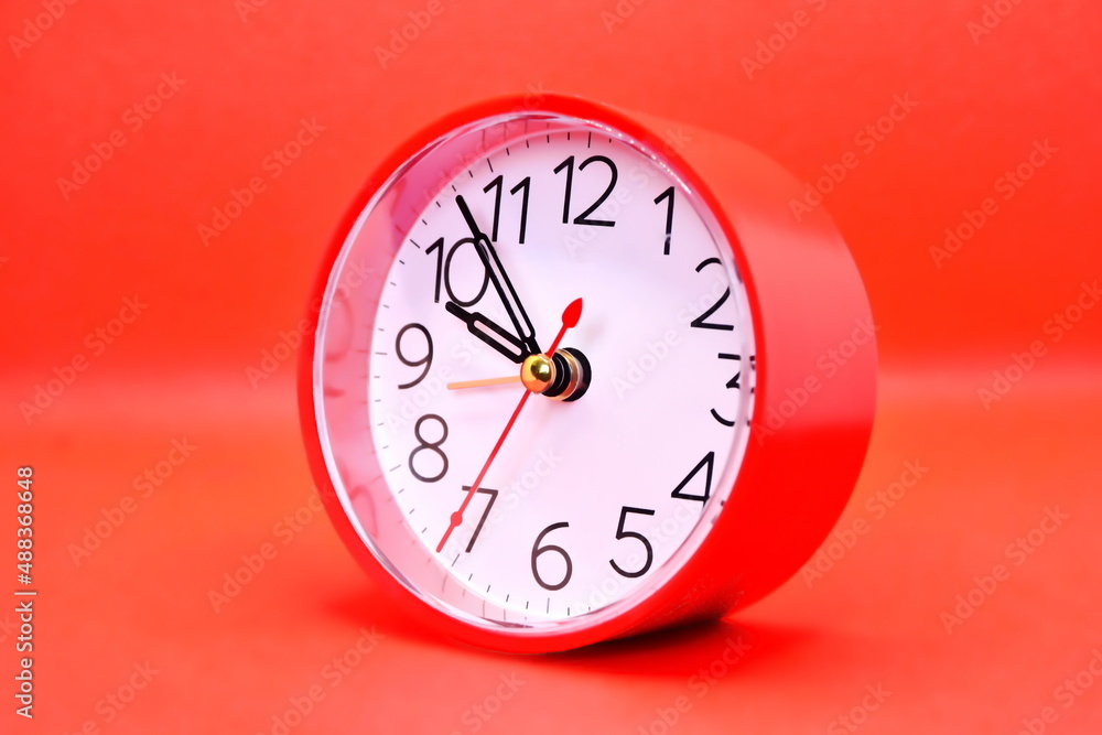 round red classic alarm clock with arrows showing the expiration of time on a red background round red classic alarm clock with arrows showing the expiration of time on a red background