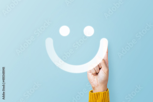 Hand of client show a feedback with smile face sign on blue background. Service rating, feedback, satisfaction concept photo