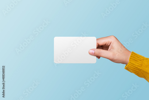Woman holding blank white card on blue background. Business concept photo
