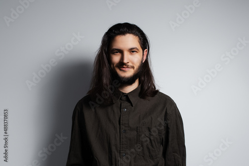 Portrait of young smiling handsome man with long hair and beard.