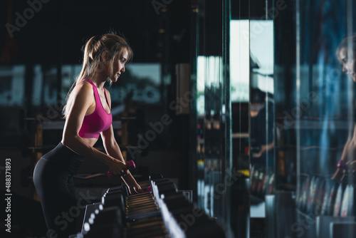 sports sexy women standing are working out with dumbbells in gym and cinematic tone process