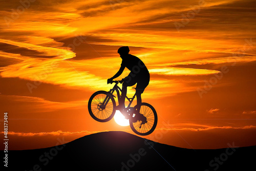 An action cyclist silhouette with the setting sun in the background. Action and adventure sports concept.