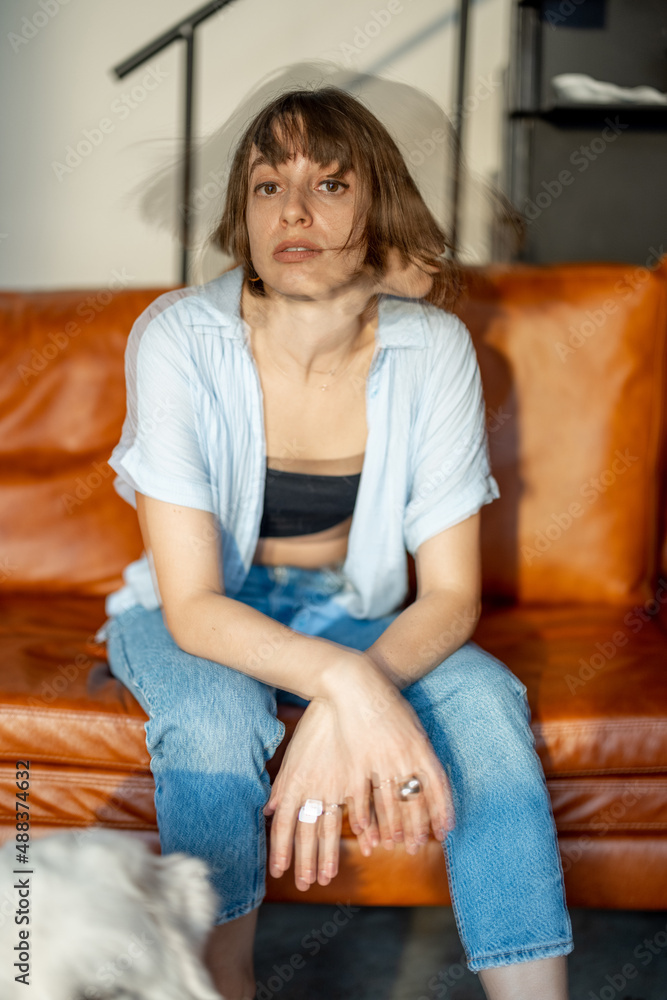 Fototapeta premium Portrait of a young confident woman sitting on couch at home. Double exposure image technic
