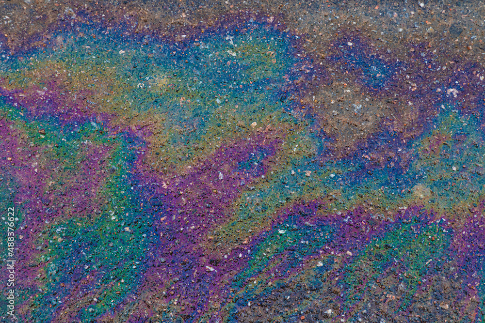 Bright, vivid and colorful backgrond or backdrop of oil, gas or petrol rainbow spots on asphalt or bitumen surface
