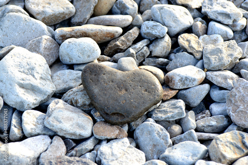 Heart shape stone against background of beach. Summer sunny day. Love, wedding and Valentine day concept. Finding beautiful and interesting stones. Beach vacation. 