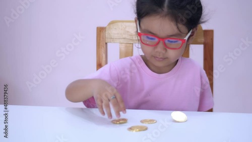 Slow motion scene of a 5-year-old Asian girl collecting bitcoins. fun at the table