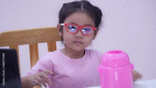 Slow motion scene of a 5-year-old Asian girl collecting bitcoins. fun at the table