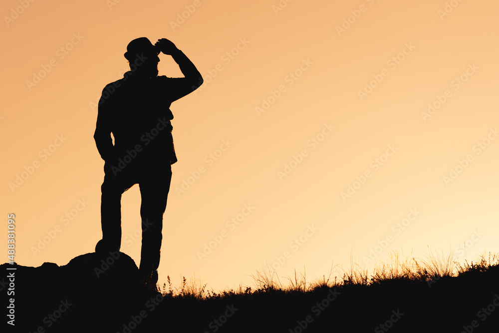 the silhouette of man standing on orange background looking to future