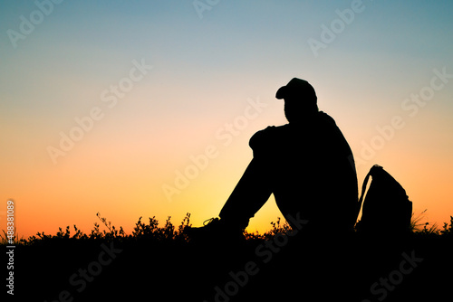 the silhouette of person sitting on ground, rest of traveler in nature