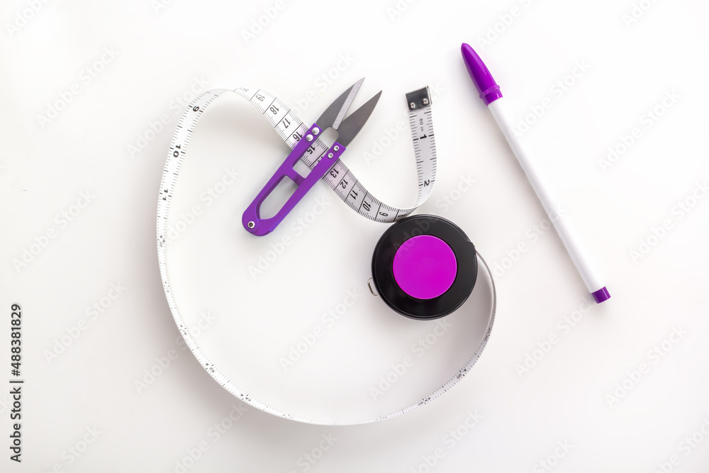 Tailor's tape measure with a thread cutter and a marker on a white background. View from above Tailor's tape measure with a thread cutter and a marker on a white background. View from above