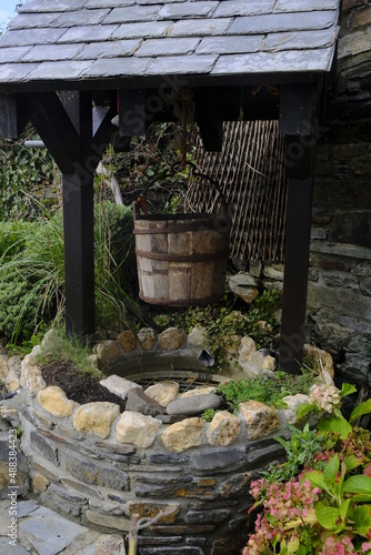 An old wooden bucket raised above a decorative, vintage well in England, UK © Ambrosiniv
