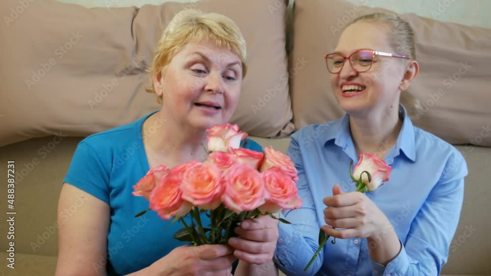Happy daughter giving flowers to her mother at home, Beautiful senior mother and daughter smiling, happy mother's day Happy daughter giving flowers to her mother at home, Beautiful senior mother and daughter smiling, happy mother's day