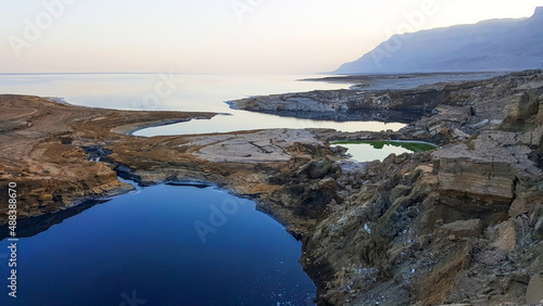 View of Dead Sea coastline. Salt crystals at sunset. Texture of Dead sea. Salty sea shore. Landscape Dead Sea coastline with natural relief channels in summer day, failures of the soil