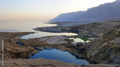 View of Dead Sea coastline. Salt crystals at sunset. Texture of Dead sea. Salty sea shore. Landscape Dead Sea coastline with natural relief channels in summer day, failures of the soil