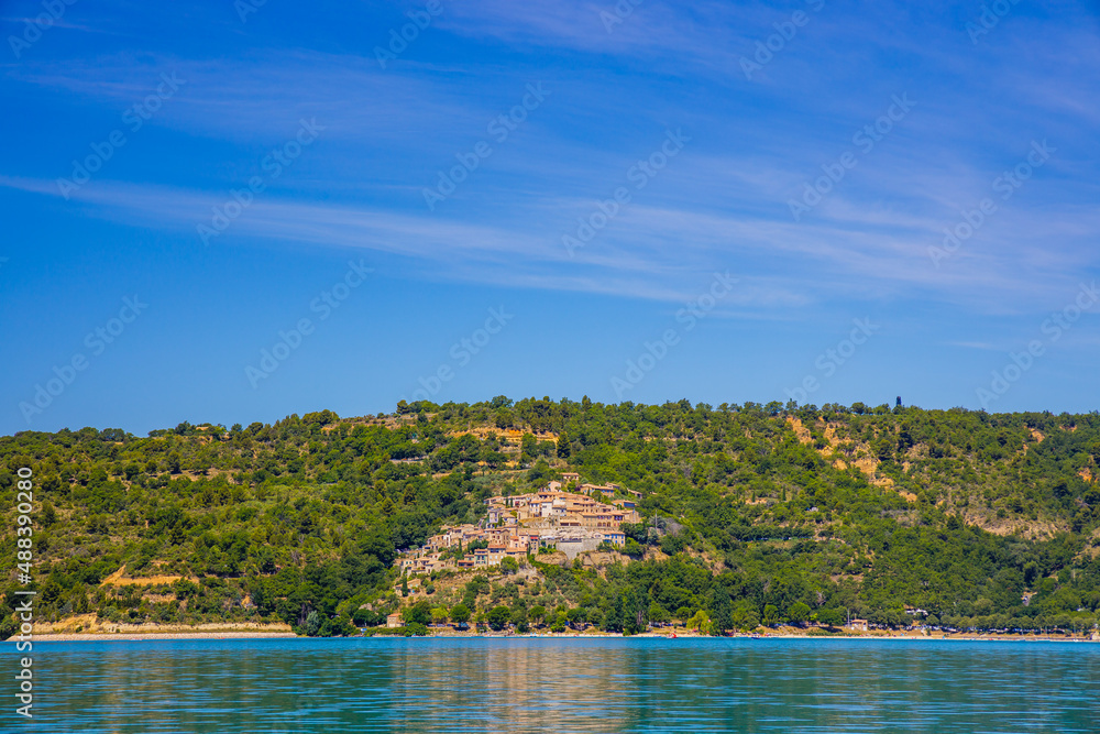 Village of Sainte-Croix-du-Verdon perched on a hill seen from the Lake of Sainte-Croix in Alpes-de-Haute-Provence, France