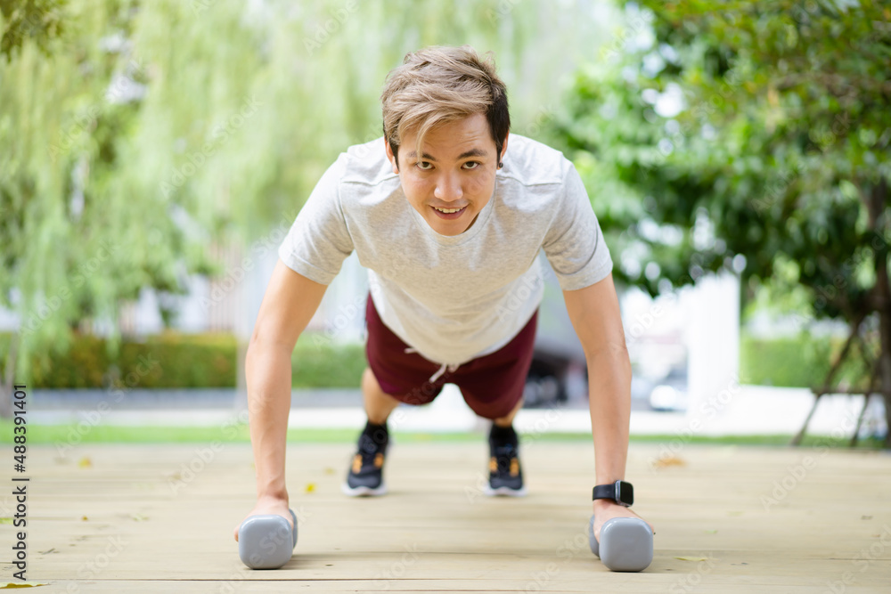 Active Asian sportsman making a body weight exercise, man doing push up workout with dumbbell. Active Asian sportsman making a body weight exercise, man doing push up workout with dumbbell.