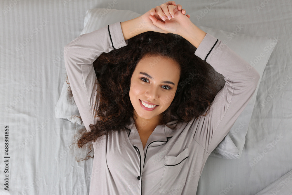 Beautiful African American woman lying in bed, top view