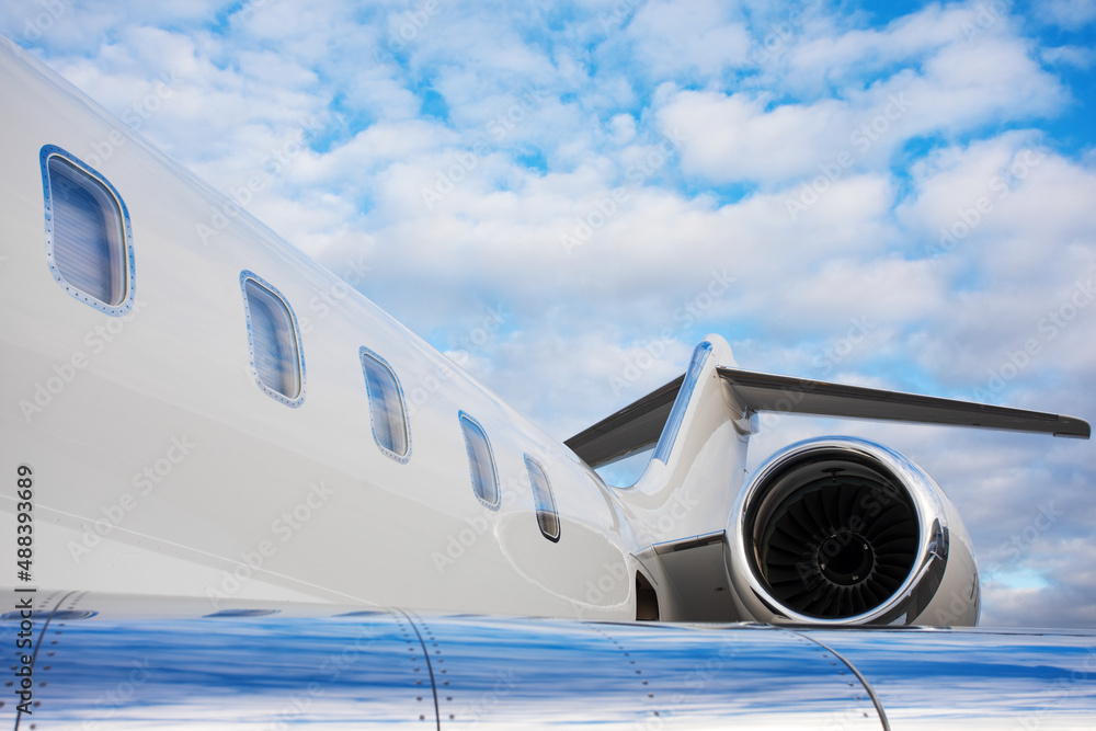 part of modern private business jet airplane with a tail and wing over sky background part of modern private business jet airplane with a tail and wing over sky background