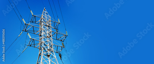 High voltage pole over blue sky, panoramic layout
