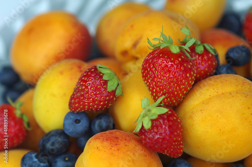 Apricots  strawberries and blueberries on a plate