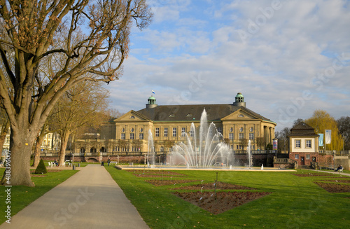 Der Rosengarten mit der großen Wasserfontäne in Bad Kissingen mit dem Staatsbad im Hintergrund bei schönem Frühlingswetter