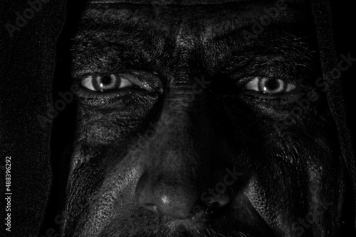 Foto Viking man with a furious gaze and a painted face looks into the darkness with b