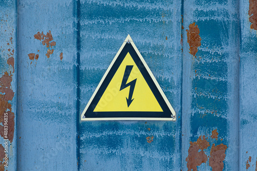Black caution or warning fire triangle sign on yellow background or table on the old painted steel wall