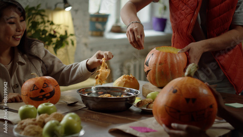 Friends are carving their pumpkins for a Halloween party photo