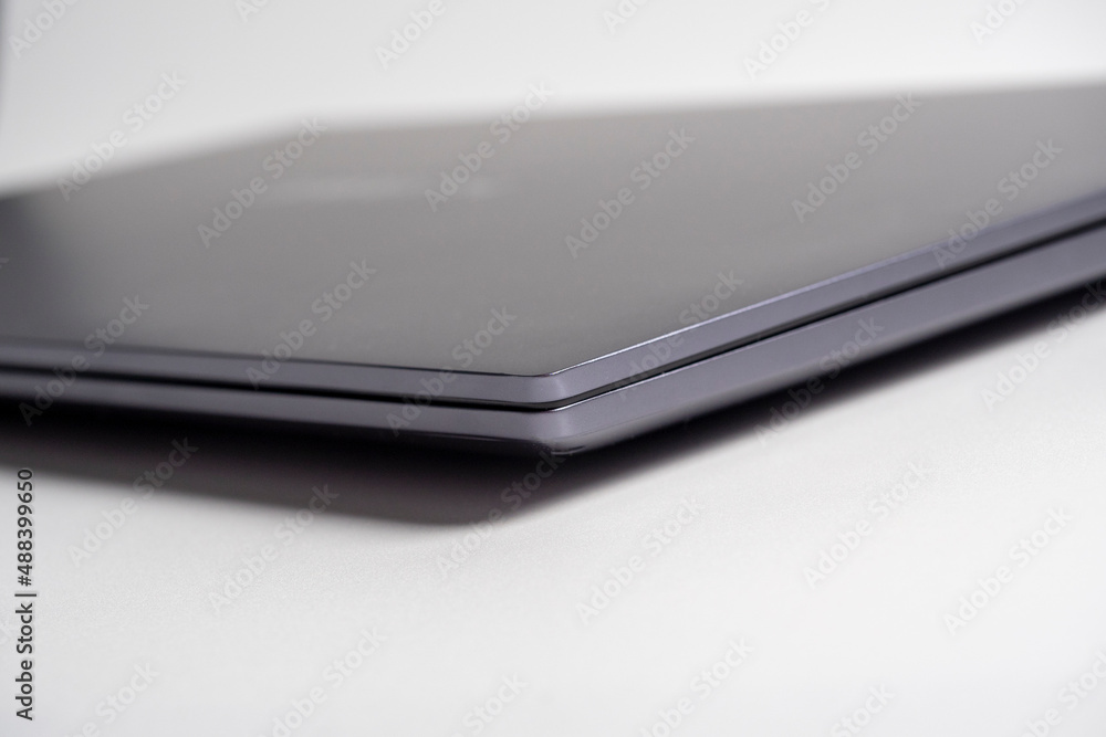 Close-up of a gray modern laptop. Side view, closed laptop. Selective focus. The concept of devices for work and leisure Close-up of a gray modern laptop. Side view, closed laptop. Selective focus. The concept of devices for work and leisure