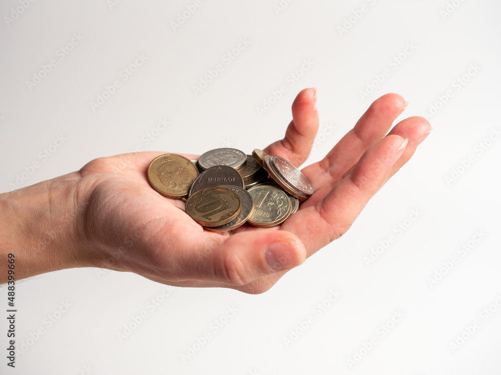 Close-up of a palm with a bunch of coins on a white background. Rubles, the concept of an economic crisis and the depreciation of money. Poverty, side view Close-up of a palm with a bunch of coins on a white background. Rubles, the concept of an economic crisis and the depreciation of money. Poverty, side view