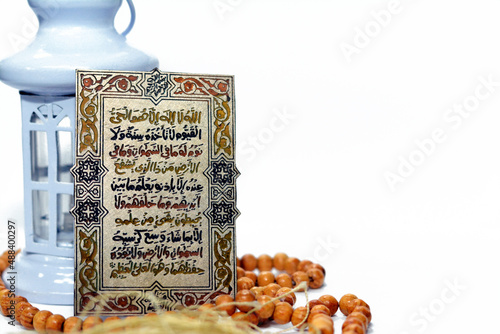 Selective focus of Ramadan fanous lantern, Islamic rosary and Al Kursi verse, the greatest verse in Quran, Translation (Allah, There is no god but He, the living, the self- subsisting, the eternal) photo