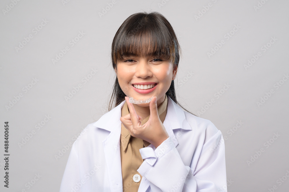 Young female dentist holding invisalign braces over white background studio, dental healthcare and Orthodontic concept. Young female dentist holding invisalign braces over white background studio, dental healthcare and Orthodontic concept.