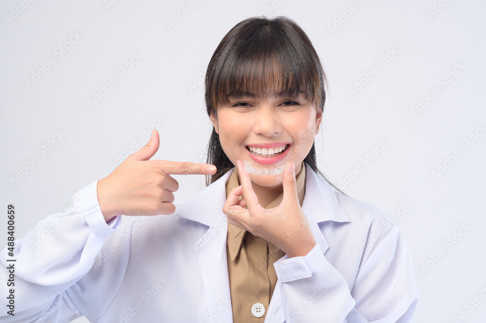 Young female dentist holding invisalign braces over white background studio, dental healthcare and Orthodontic concept. Young female dentist holding invisalign braces over white background studio, dental healthcare and Orthodontic concept.