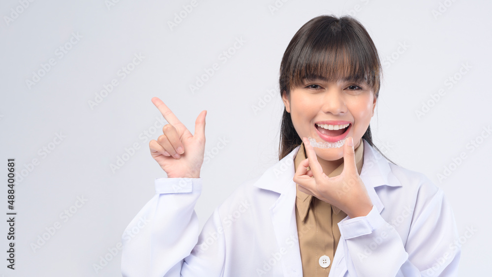 Young female dentist holding invisalign braces over white background studio, dental healthcare and Orthodontic concept. Young female dentist holding invisalign braces over white background studio, dental healthcare and Orthodontic concept.