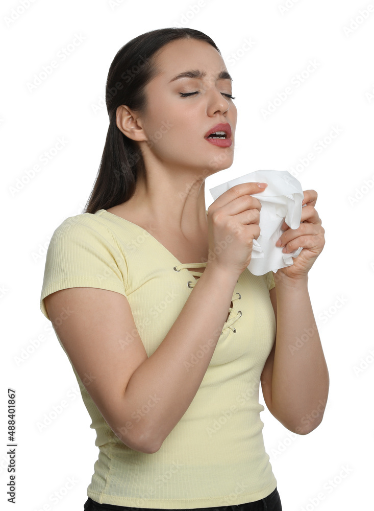 Sick young woman sneezing in tissue on white background. Cold symptoms