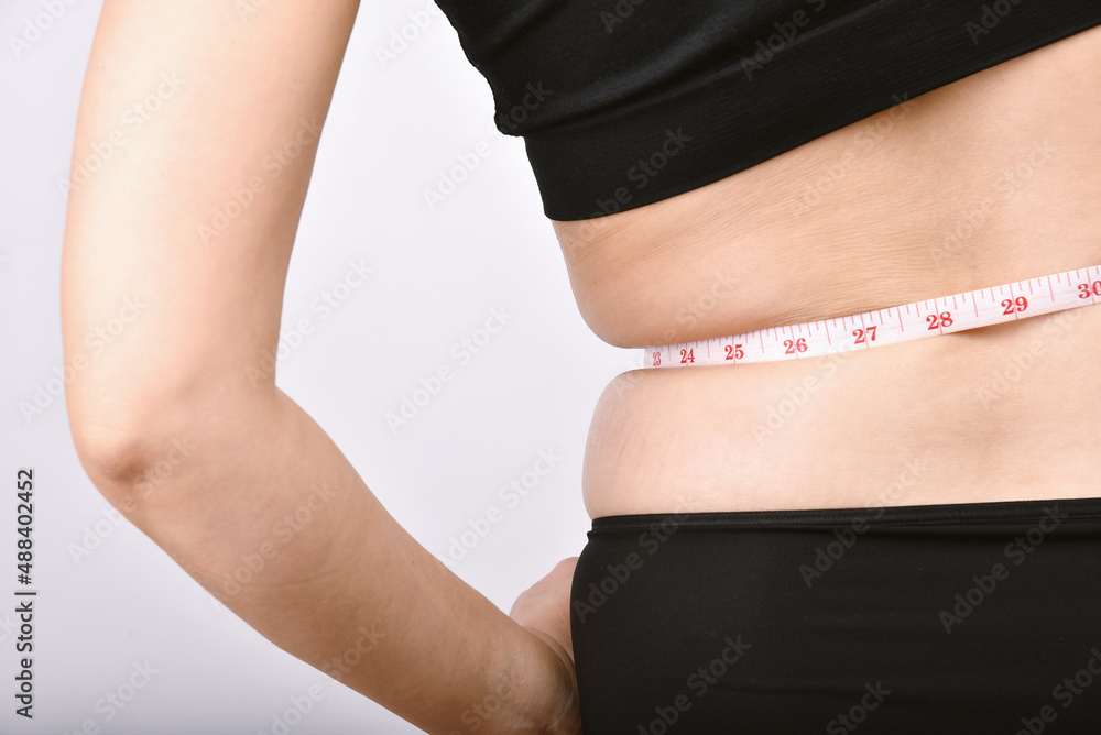 Fat woman measuring her belly fat, Overweight woman check out her obesity, Woman muffin top waistline.