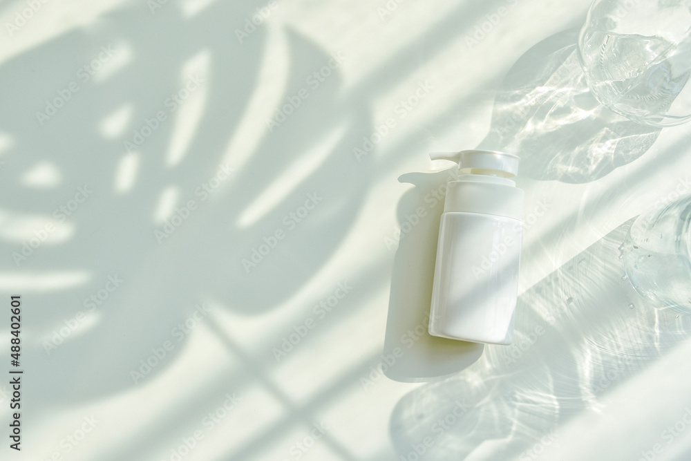 Cosmetic bottle containers packaging with green herbal leaves in shadow and light effect, Blank label for organic branding mock-up, Natural skincare beauty product concept.