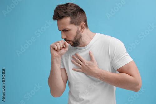 Obraz na plátně Man coughing on light blue background. Cold symptoms