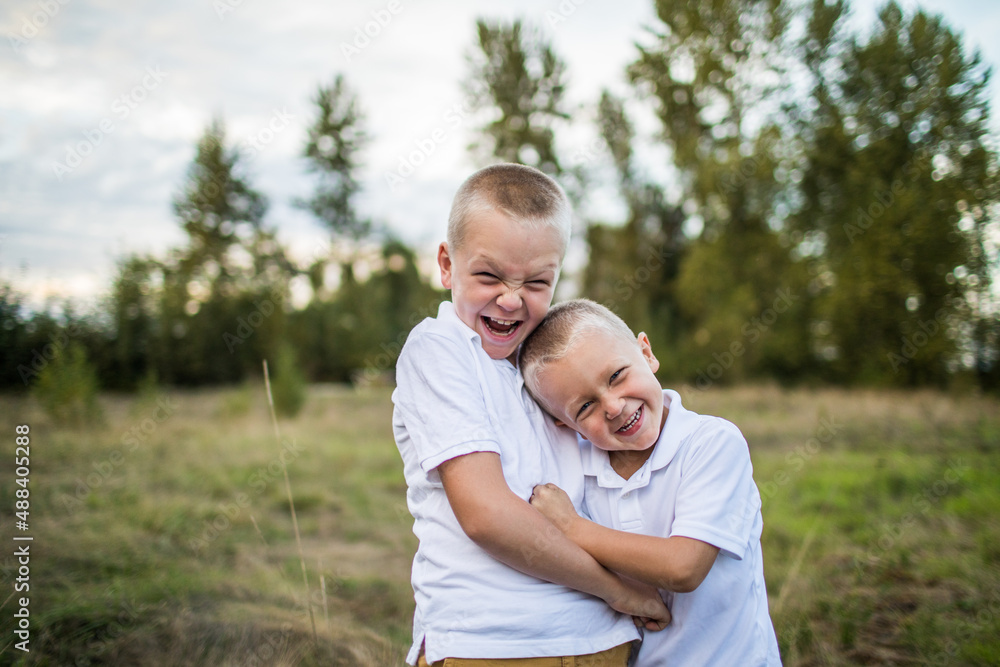 Brothers playfully wrestle outdoors in grassy field Brothers playfully wrestle outdoors in grassy field