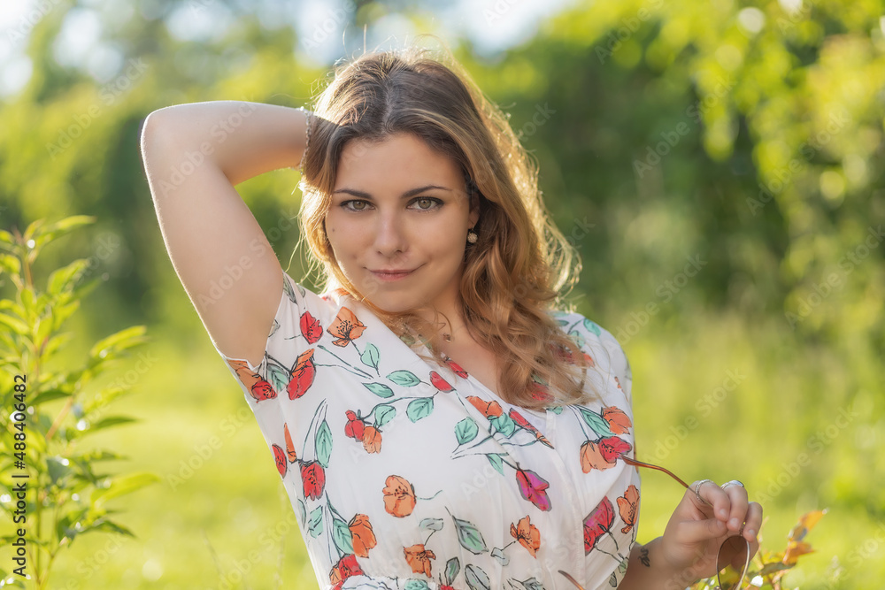 Atractive long hair young woman with both hands in her hair is posing outdoors. Horizontally. Atractive long hair young woman with both hands in her hair is posing outdoors. Horizontally.