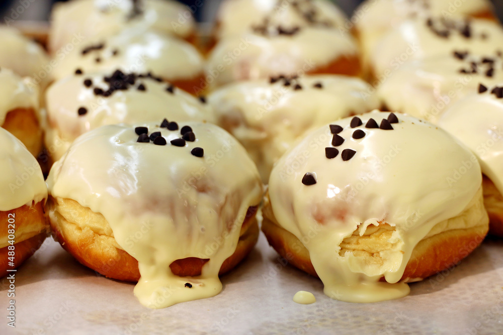 Doughnuts in cream sauce close up, high calorie food. Sweet glazed donuts sprinkled with chocolate chips in a store Doughnuts in cream sauce close up, high calorie food. Sweet glazed donuts sprinkled with chocolate chips in a store