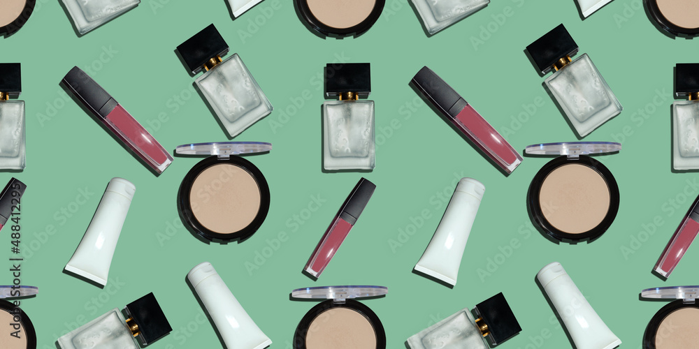 flat lay of cream tubes with hand cream, mascara bottle with oil, cosmetic glass bottles, cosmetic dispensers and jars on green