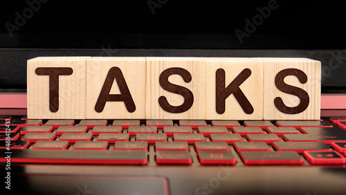 TASKS the inscription on wooden cubes on the illuminated laptop keyboard. Business concept