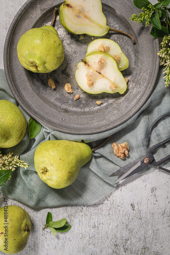 Tasty pears with nuts. A table decorated with flowers and a plate of pears cut into the plate