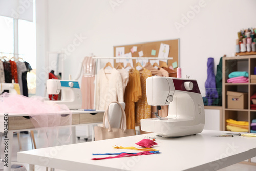 Sewing machine and accessories on table in dressmaking workshop photo