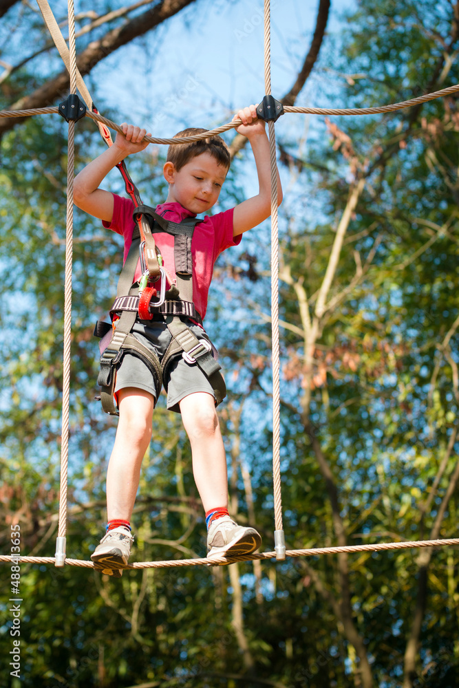 young boy navigating treetop ropes course